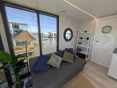 a living room with a couch and a large window at Gezellige houseboat Eclipse Monnickendam nabij Amsterdam in Monnickendam