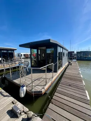 a small boat is docked at a dock at Gezellige houseboat Eclipse Monnickendam nabij Amsterdam in Monnickendam