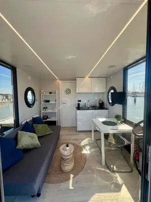 a living room with a couch and a table at Gezellige houseboat Eclipse Monnickendam nabij Amsterdam in Monnickendam
