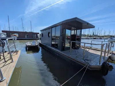 a small boat parked at a dock in the water at Gezellige houseboat Eclipse Monnickendam nabij Amsterdam in Monnickendam