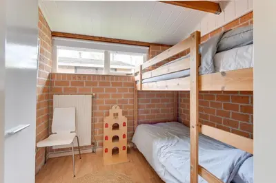 a small room with a bunk bed and a chair at Vakantiehuis met strand Noord-holland op 5 min & ruime tuin VP078 in Warmenhuizen
