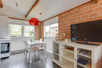 a kitchen with a table and a tv and a brick wall at Vakantiehuis met strand Noord-holland op 5 min & ruime tuin VP078 in Warmenhuizen