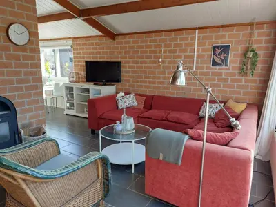 a living room with a red couch and a brick wall at Vakantiehuis met strand Noord-holland op 5 min & ruime tuin VP078 in Warmenhuizen