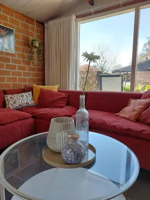 a living room with a red couch and a glass table at Vakantiehuis met strand Noord-holland op 5 min & ruime tuin VP078 in Warmenhuizen