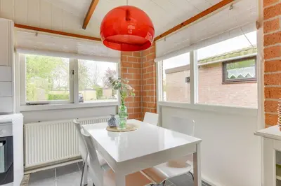 a kitchen and dining room with a white table and chairs at Vakantiehuis met strand Noord-holland op 5 min & ruime tuin VP078 in Warmenhuizen