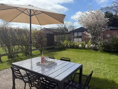 a picnic table with an umbrella in a yard at Vakantiehuis met strand Noord-holland op 5 min & ruime tuin VP078 in Warmenhuizen