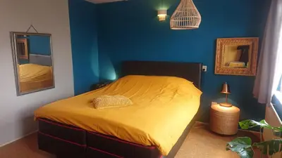 a bedroom with a yellow bed with a blue wall at House nearby Amsterdam in Almere