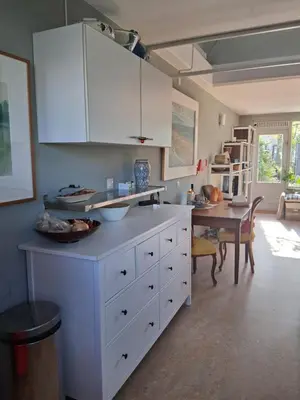 a kitchen with white cabinets and a dining table at House nearby Amsterdam in Almere
