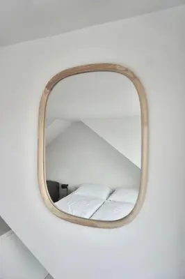 a mirror hanging on a wall with a bed at Bed & Beach 114 in Noordwijk aan Zee