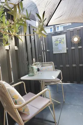 a patio with a table and chairs and a fence at Bed & Beach 114 in Noordwijk aan Zee