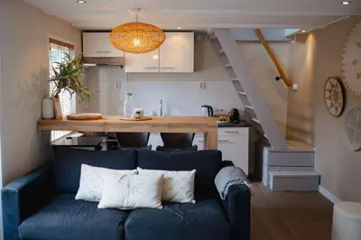 a living room with a blue couch and a kitchen at Duijnparadijs in Schoorl