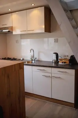 a kitchen with white cabinets and a sink at Duijnparadijs in Schoorl