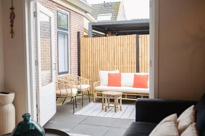 a patio with a couch and a table and chairs at Duijnparadijs in Schoorl
