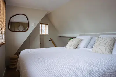 a bedroom with a white bed and a mirror at Duijnparadijs in Schoorl