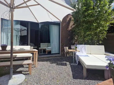 a patio with a white umbrella and a table and chairs at The Beach House in Schellinkhout