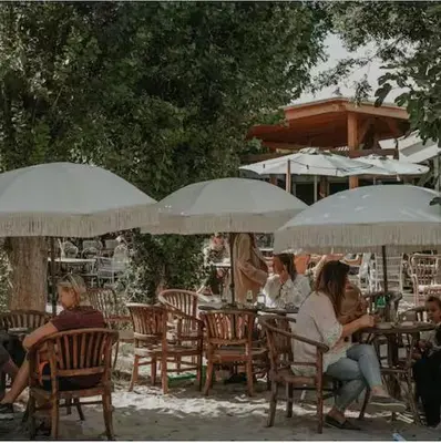 a group of people sitting at tables under umbrellas at The Beach House in Schellinkhout
