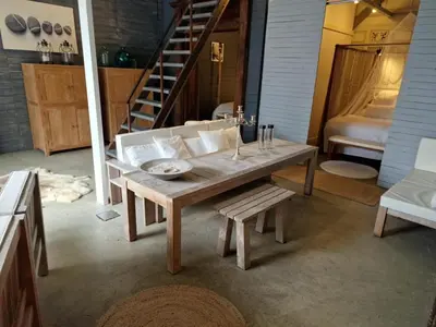 a wooden table and bench in a room with a staircase at The Beach House in Schellinkhout