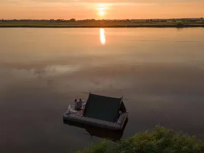 two people sitting on a boat in the water at Campingraft Katwoude in Katwoude