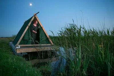 a woman is standing in a boat in the water at Campingraft Katwoude in Katwoude