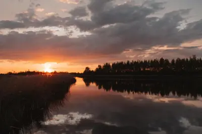 a sunset over a river with the sun setting at Campingraft Katwoude in Katwoude