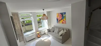 a living room with a couch and two windows at Centrally located, fully furnished luxury apartment in Gouda