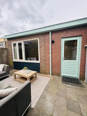 a patio with a couch and a table and a building at Bungalow at the Beach in Noordwijk aan Zee