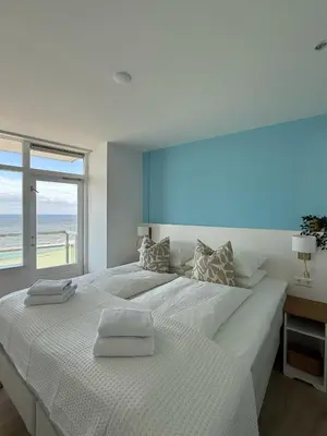 a white bedroom with a large bed with a window at Sunset Beach in Zandvoort