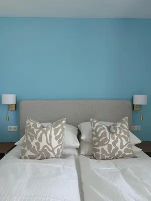a bed with white sheets and pillows with a blue background at Sunset Beach in Zandvoort