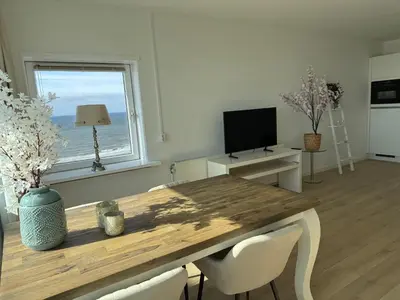 a dining room with a wooden table and a television at Sunset Beach in Zandvoort