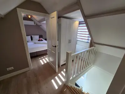 a small room with a bed and a staircase at De Juttershut in Egmond aan Zee