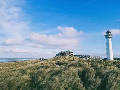 a lighthouse sitting on top of a hill next to the ocean at De Juttershut in Egmond aan Zee