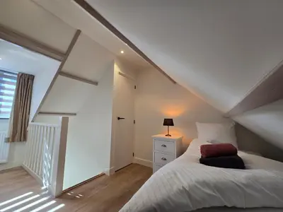 a attic bedroom with a bed and a lamp at De Juttershut in Egmond aan Zee