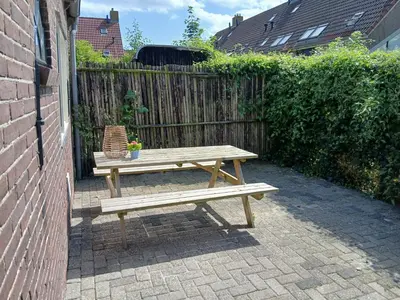 a wooden picnic table and a chair next to a fence at Vakantiewoning De 