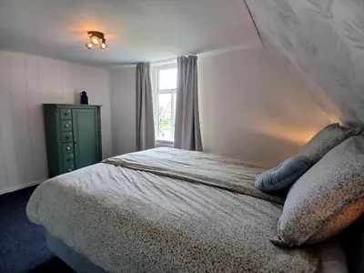 a bedroom with a bed with a green dresser and a window at Vakantiewoning De 