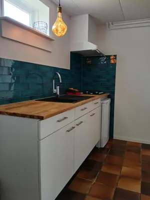 a kitchen with white cabinets and green tiles at Vakantiewoning De 