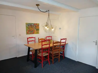 a dining room table with red chairs and a chandelier at Vakantiewoning De 