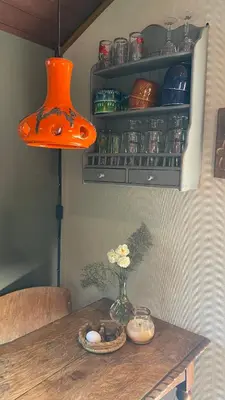 an orange light hanging over a wooden table at De Verborgen Pracht in Schagen