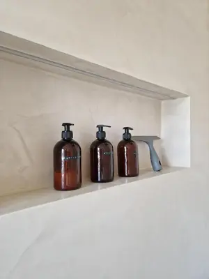 four bottles sitting on a shelf in a bathroom at Loft with parkside view in Amsterdam