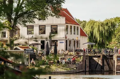a building next to a river with people sitting outside at Loft with parkside view in Amsterdam