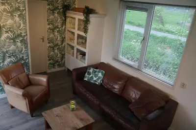a living room with a leather couch and a table at Landelijk gelegen chalet aan de Vecht vlakbij Amsterdam in Nigtevecht