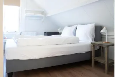 a bedroom with a bed with white sheets and a table at -Duna Lago- nabij het meer, restaurants en Keukenhof in Noordwijkerhout