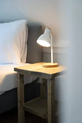 a table with a lamp on it next to a bed at -Duna Lago- nabij het meer, restaurants en Keukenhof in Noordwijkerhout
