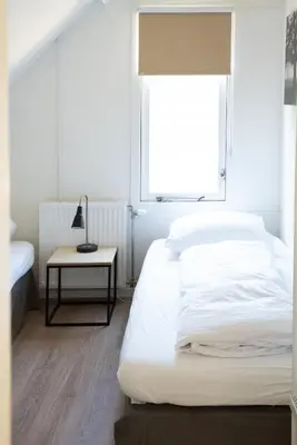 a white bedroom with a bed and a window at -Duna Lago- nabij het meer, restaurants en Keukenhof in Noordwijkerhout