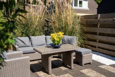 a patio with a table and a couch and flowers at -Duna Lago- nabij het meer, restaurants en Keukenhof in Noordwijkerhout