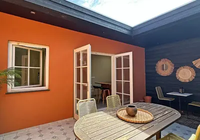 a dining room with an orange wall and a wooden table at Beach Hide-out Zandvoort in Zandvoort