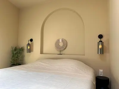a bedroom with a white bed with an arched window at Beach Hide-out Zandvoort in Zandvoort