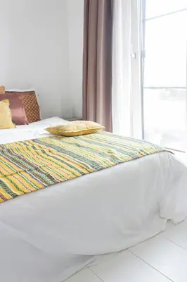 a white bed with a yellow pillow and a window at Lovely cozy houseboat Rembrandt, old centre Leiden in Leiden
