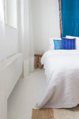 a white bedroom with a bed with blue pillows at Lovely cozy houseboat Rembrandt, old centre Leiden in Leiden