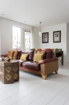 a living room with a brown couch and a table at Lovely cozy houseboat Rembrandt, old centre Leiden in Leiden