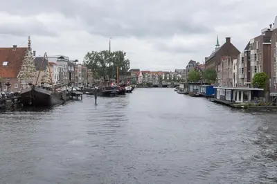 a river with houses and boats in a city at Lovely cozy houseboat Rembrandt, old centre Leiden in Leiden